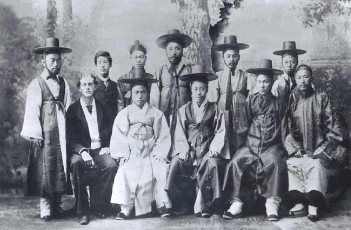 A group of Korean delegates mostly wearing traditional Korean attire pose together for a formal photo.