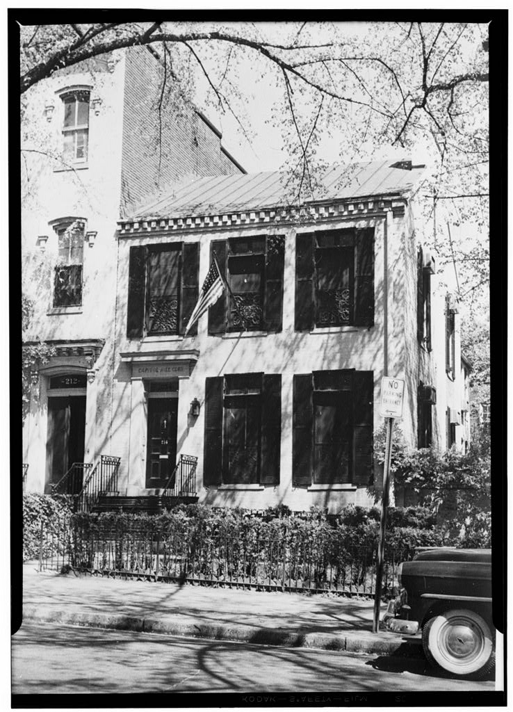 Archival photograph of a rowhouse with an American flag displayed by the door.