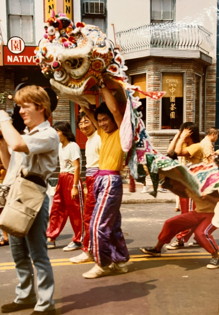 A Lion Dance performer holds a lion head above his head while smiling for the camera in Washington, D.C.'s Chinatown.