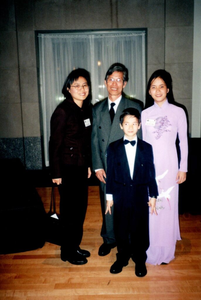 A group of two adults and two young people wearing evening attire pose for a photo at an event.