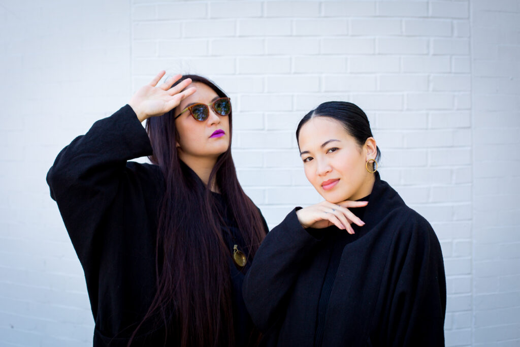 Two women wearing black pose for a photo.