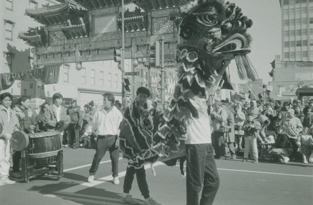 Performers with a Lion Dance costume and drums parade in front of the Chinatown Friendship Archway.